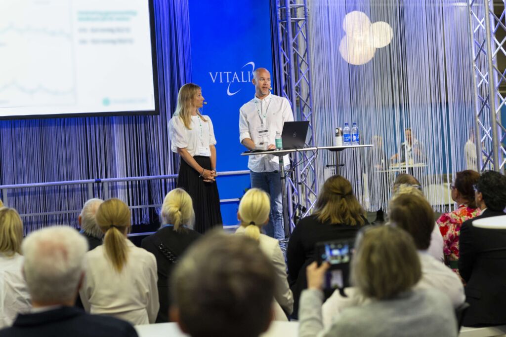 Two speakers are presenting on the Vitalis Plaza stage at the Vitalis trade fair, in front of an audience.